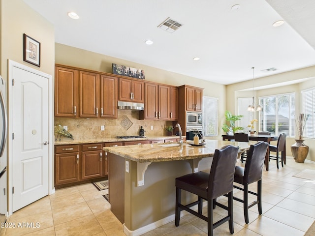 kitchen featuring visible vents, stainless steel appliances, decorative backsplash, and a sink