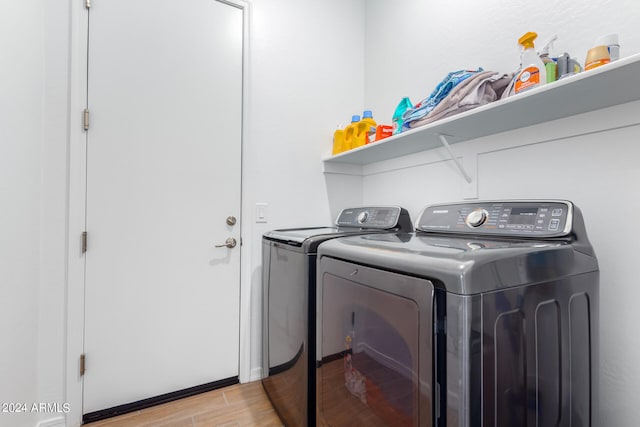 laundry area with washing machine and clothes dryer and light hardwood / wood-style flooring