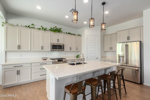 kitchen with a kitchen island with sink, sink, light hardwood / wood-style floors, and high quality appliances