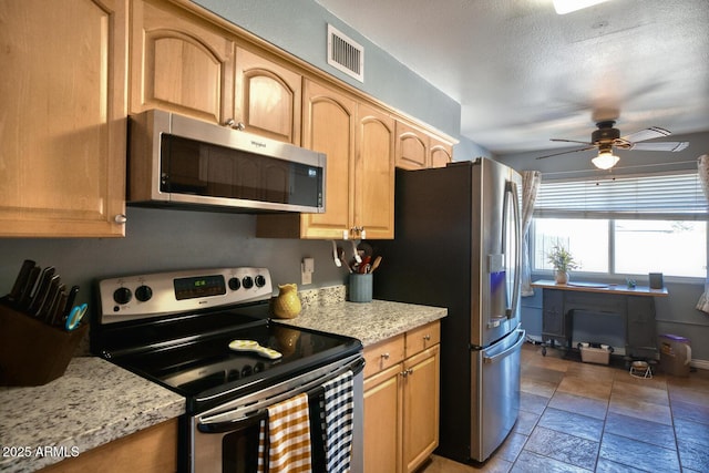kitchen with ceiling fan, appliances with stainless steel finishes, light stone counters, stone tile floors, and visible vents
