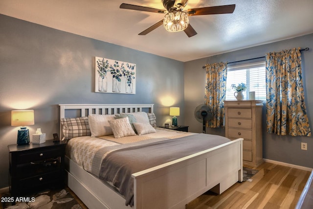 bedroom with baseboards, a ceiling fan, and light wood finished floors