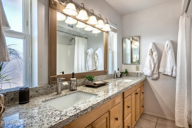 full bathroom with double vanity, tile patterned floors, and a sink