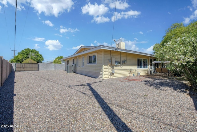 back of property with a chimney, a gate, central air condition unit, fence, and a patio
