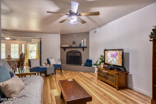 living room with ceiling fan, a brick fireplace, wood finished floors, and visible vents