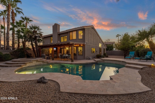 pool at dusk featuring an in ground hot tub and a patio area