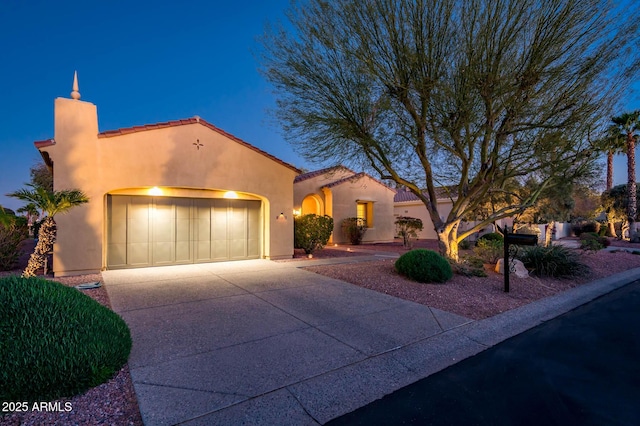 mediterranean / spanish house featuring a tile roof, a chimney, stucco siding, concrete driveway, and a garage