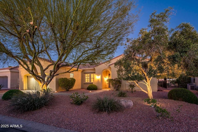 view of front of house featuring central AC unit, an attached garage, and stucco siding