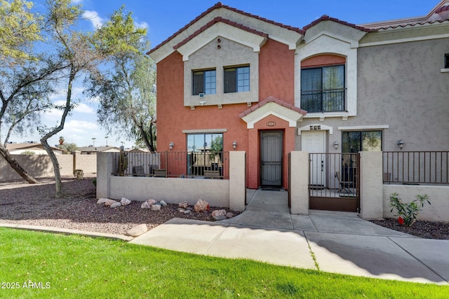 view of front of property featuring a gate, a fenced front yard, a tiled roof, and stucco siding