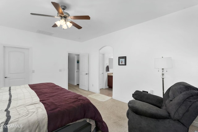 bedroom featuring visible vents, light carpet, ensuite bath, arched walkways, and baseboards