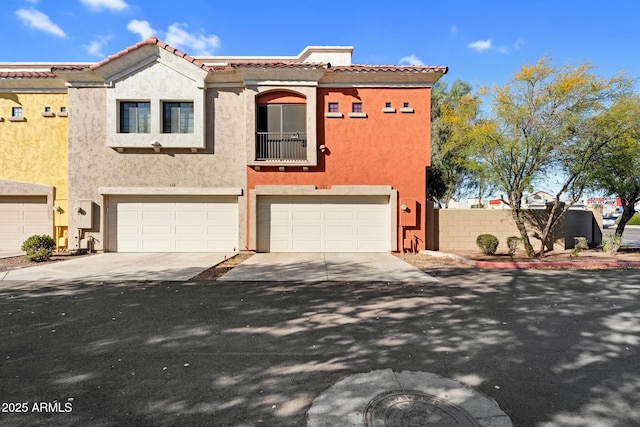 view of front of house featuring stucco siding, a tiled roof, concrete driveway, and a garage