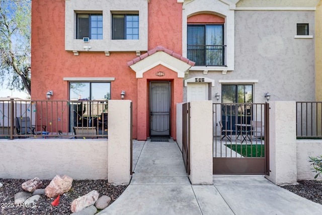 view of front facade featuring stucco siding, fence, and a gate