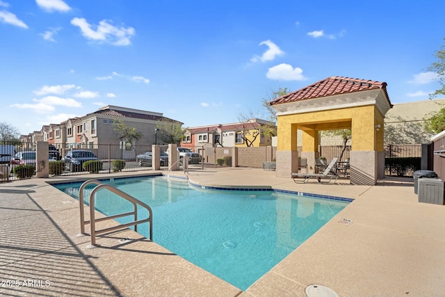 pool with a patio area, a residential view, and fence