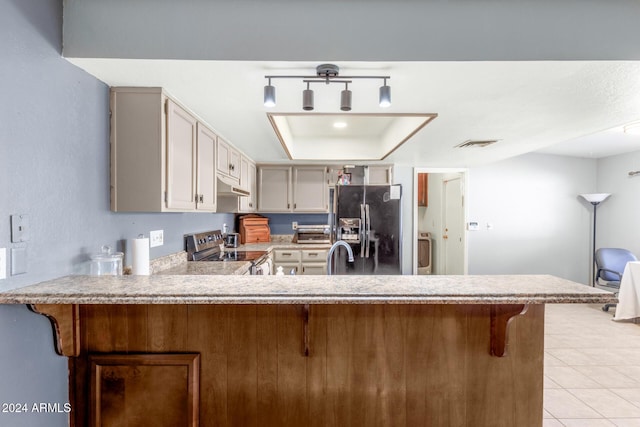 kitchen featuring stainless steel electric range oven, black refrigerator with ice dispenser, kitchen peninsula, a breakfast bar area, and light tile patterned floors