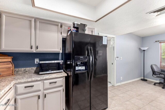 kitchen featuring white cabinets, black fridge with ice dispenser, light tile patterned floors, and a textured ceiling