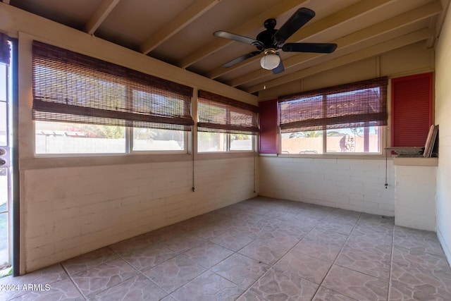 unfurnished sunroom featuring beamed ceiling and ceiling fan