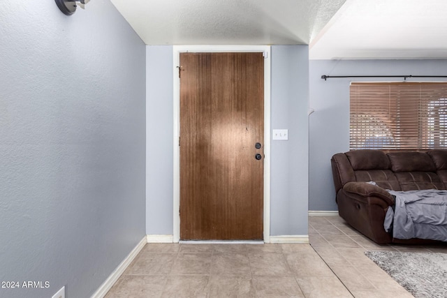 foyer entrance with light tile patterned flooring and a textured ceiling