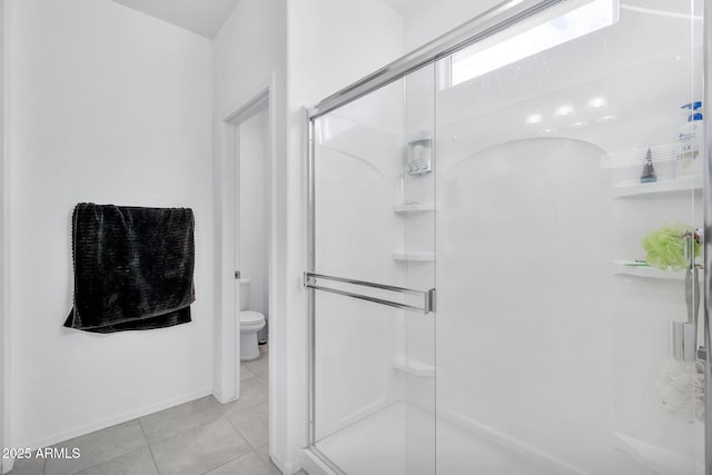 bathroom featuring tile patterned flooring, toilet, and a shower with shower door