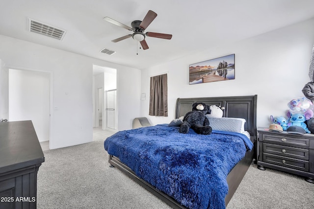 bedroom with ceiling fan, light colored carpet, and ensuite bathroom