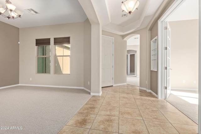 carpeted foyer entrance with an inviting chandelier