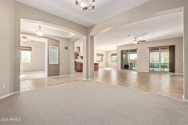 interior space with ceiling fan with notable chandelier and light colored carpet