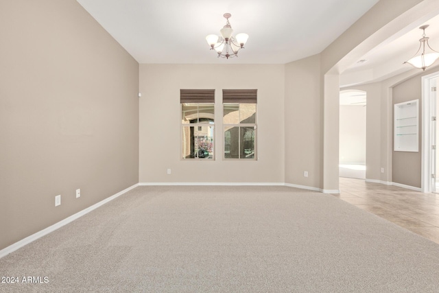 spare room featuring a notable chandelier and light colored carpet