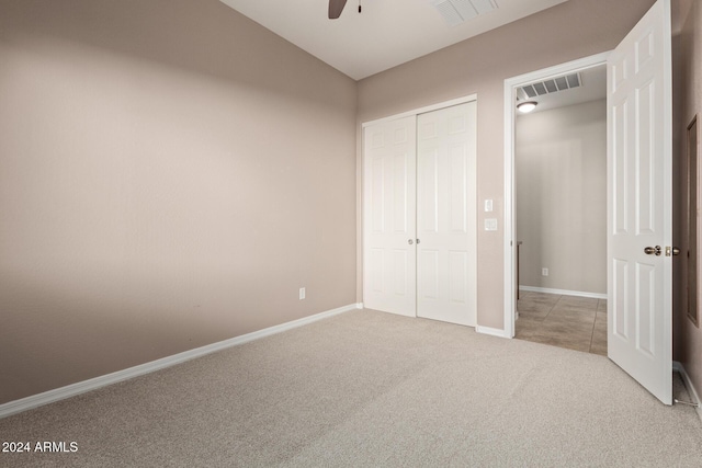 unfurnished bedroom featuring ceiling fan, light carpet, and a closet