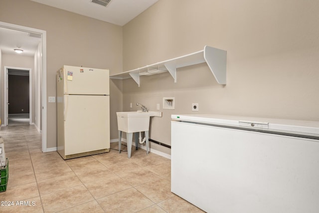 washroom with hookup for an electric dryer, light tile patterned floors, sink, and washer hookup