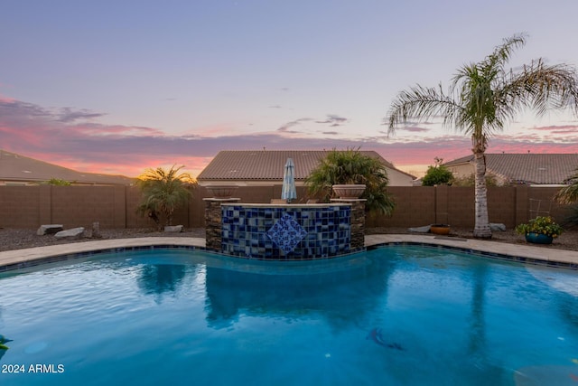 pool at dusk featuring pool water feature