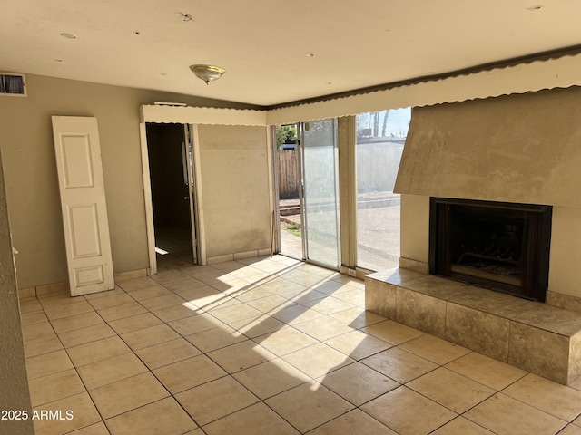 unfurnished living room with light tile patterned flooring, a tile fireplace, and visible vents