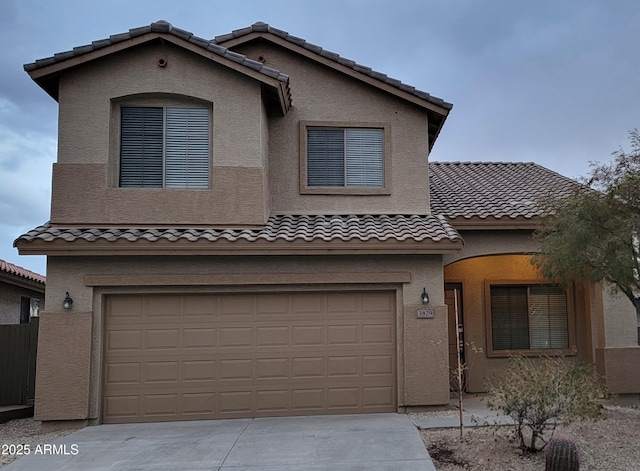 view of front of property with concrete driveway, a tile roof, an attached garage, and stucco siding