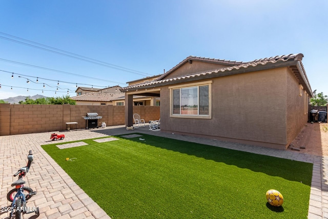 rear view of house with a patio area, a tiled roof, and stucco siding