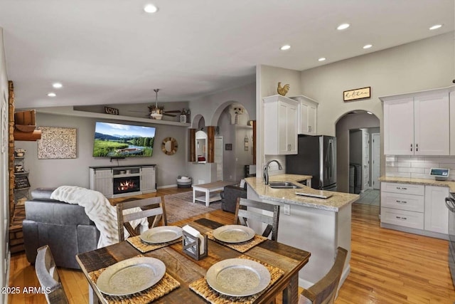 dining area with vaulted ceiling, ceiling fan, sink, and light wood-type flooring