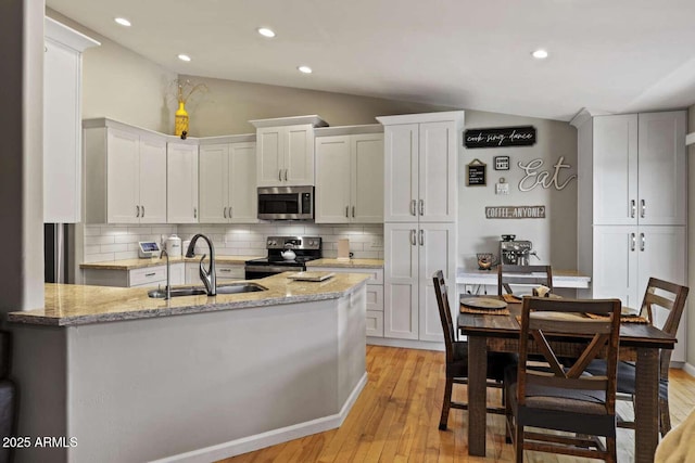 kitchen featuring lofted ceiling, sink, white cabinetry, stainless steel appliances, and decorative backsplash