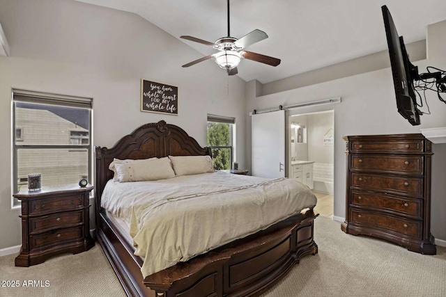 carpeted bedroom with a barn door, connected bathroom, lofted ceiling, and ceiling fan