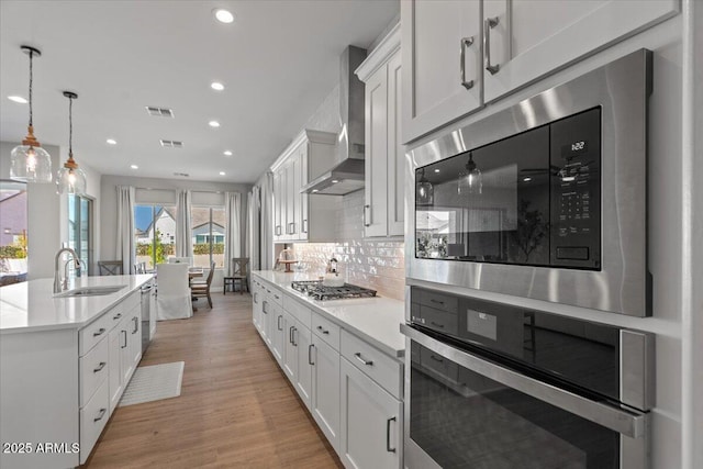 5860 E Sanford St, Mesa, AZ 85215 - kitchen featuring wall chimney range hood, light countertops, light wood-style floors, stainless steel appliances, and a sink