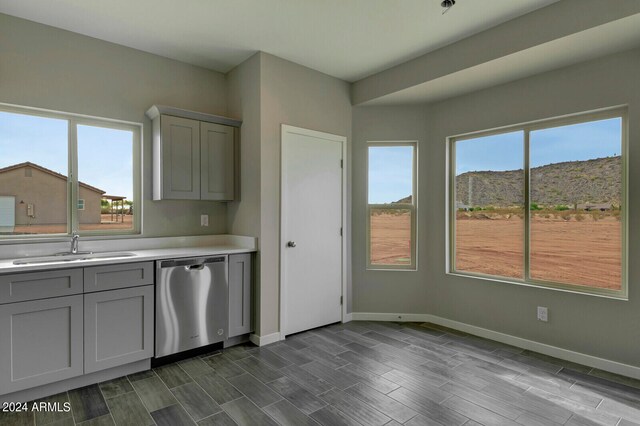 kitchen with gray cabinets, a mountain view, stainless steel dishwasher, and sink