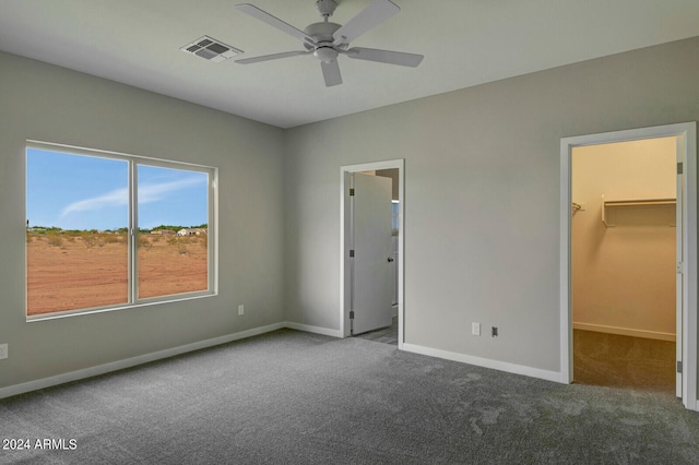 unfurnished bedroom with a closet, ceiling fan, carpet, and a walk in closet