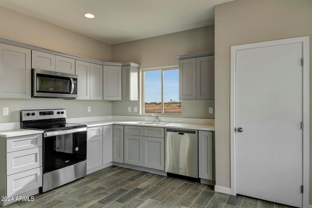 kitchen featuring gray cabinetry, appliances with stainless steel finishes, sink, and dark wood-type flooring