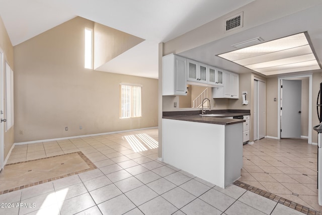 kitchen featuring white cabinets, light tile patterned floors, vaulted ceiling, and sink