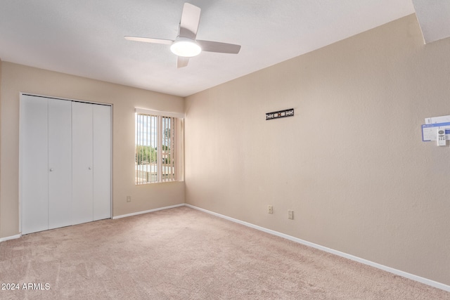 unfurnished bedroom featuring a closet, light colored carpet, and ceiling fan