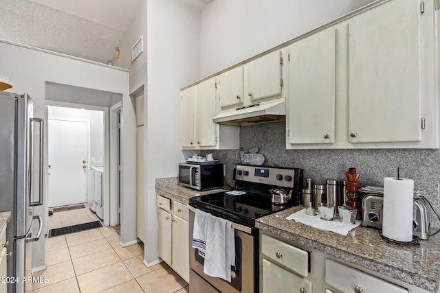 kitchen with stainless steel appliances, cream cabinets, a textured ceiling, washer / dryer, and light tile patterned floors