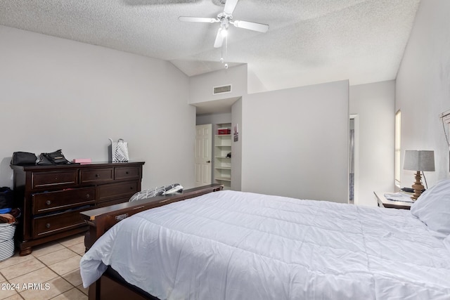 tiled bedroom featuring ceiling fan, a textured ceiling, and vaulted ceiling