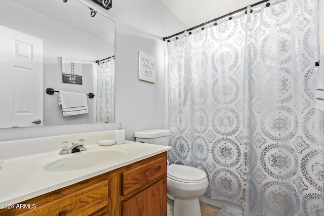 bathroom featuring tile patterned flooring, vanity, toilet, and vaulted ceiling