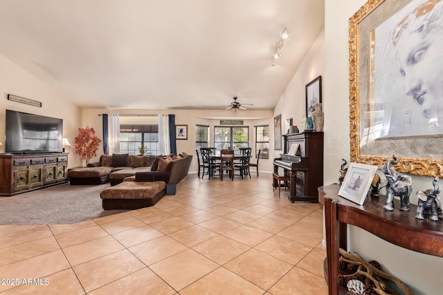 living room featuring ceiling fan, light tile patterned floors, rail lighting, and lofted ceiling