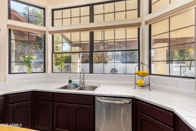 kitchen featuring dark brown cabinets, tile counters, dishwasher, and sink