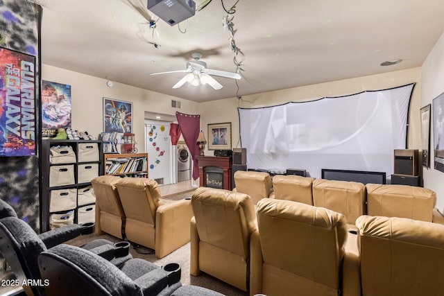 carpeted cinema room with ceiling fan, washer / clothes dryer, and a fireplace