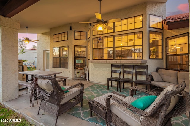 patio terrace at dusk featuring ceiling fan and an outdoor living space