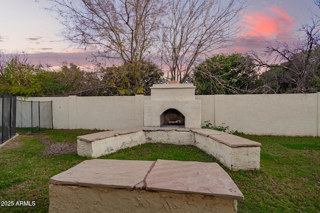 yard at dusk with exterior fireplace