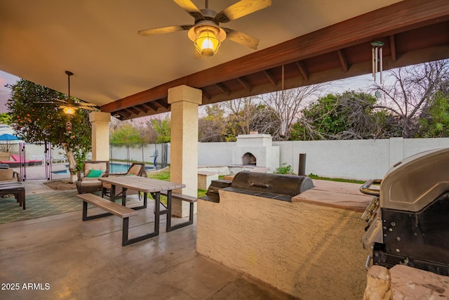 view of patio featuring an outdoor fireplace, an outdoor kitchen, a fenced in pool, area for grilling, and a water view