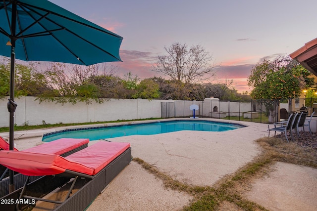 pool at dusk featuring a patio